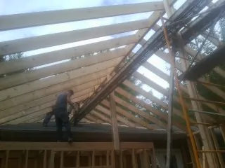 Rafters going up over a new addition with a worker on the wall in Linthicum Heights