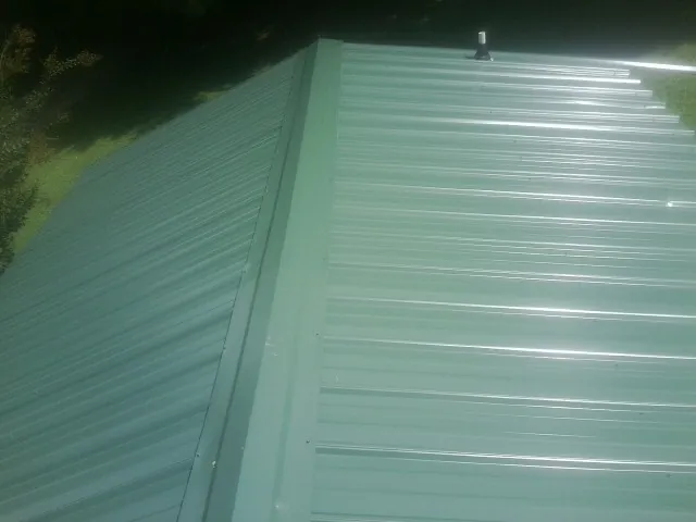 New green metal panels meeting at the ridge of a roof — Flat Roof Repair work by our crew in Linthicum Heights