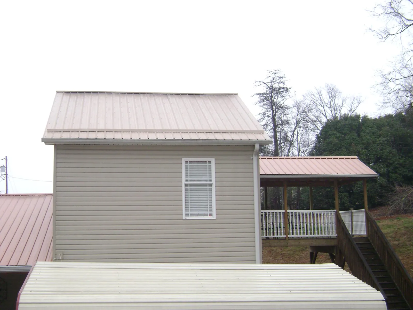 Tan metal roofs on a two story addition and attached porch, from a Roof Replacement job in Linthicum Heights