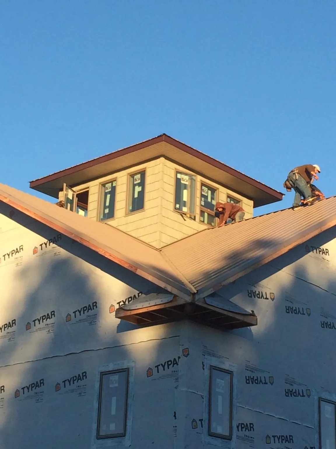 Roofers working around a rooftop cupola on a new metal roof at sunset — Roof Waterproofing in Linthicum Heights by Roofing Brothers